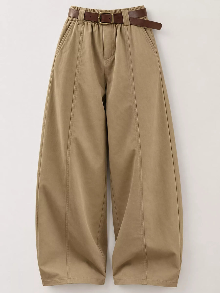 A pair of wide-leg, pleated khaki pants with a brown leather belt, displayed flat against a light gray background.