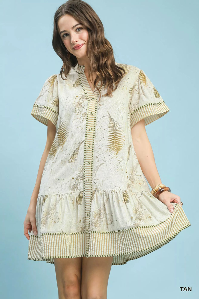 Woman wearing a beige and white embroidered dress against a light blue background