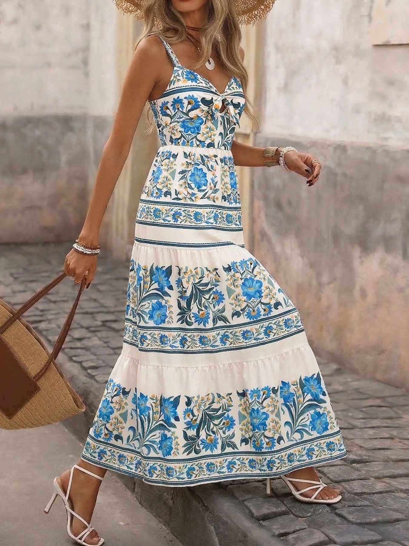 Woman wearing a floral dress walking on a cobblestone street.
