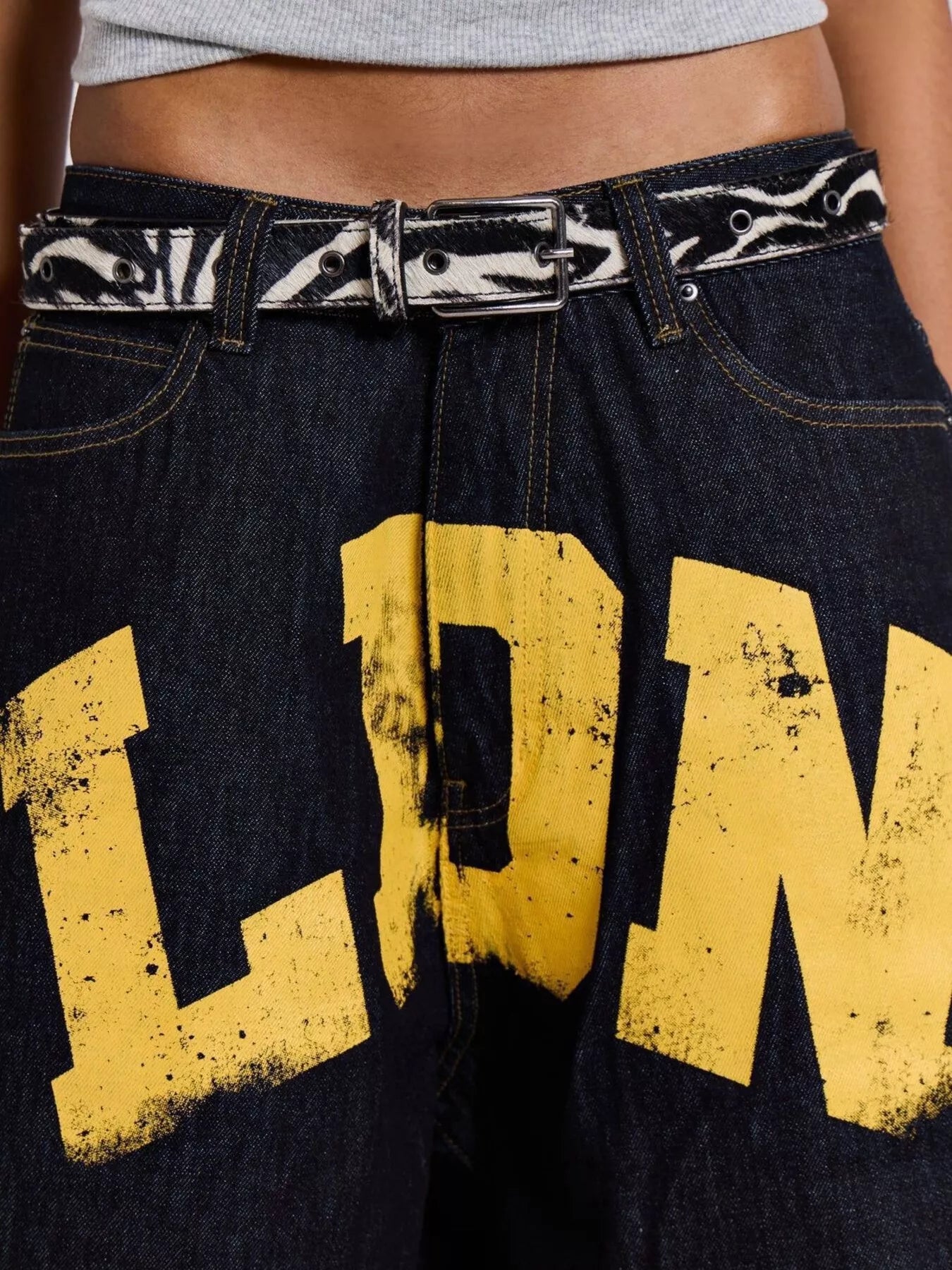 Black jeans with yellow text and a decorative belt