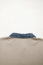 Close-up of a beige garment with a blue denim collar on a white background