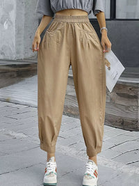 Person wearing beige high-waisted pants on a stone pavement.