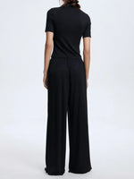 Person wearing a black outfit with wide-leg pants on a white background
