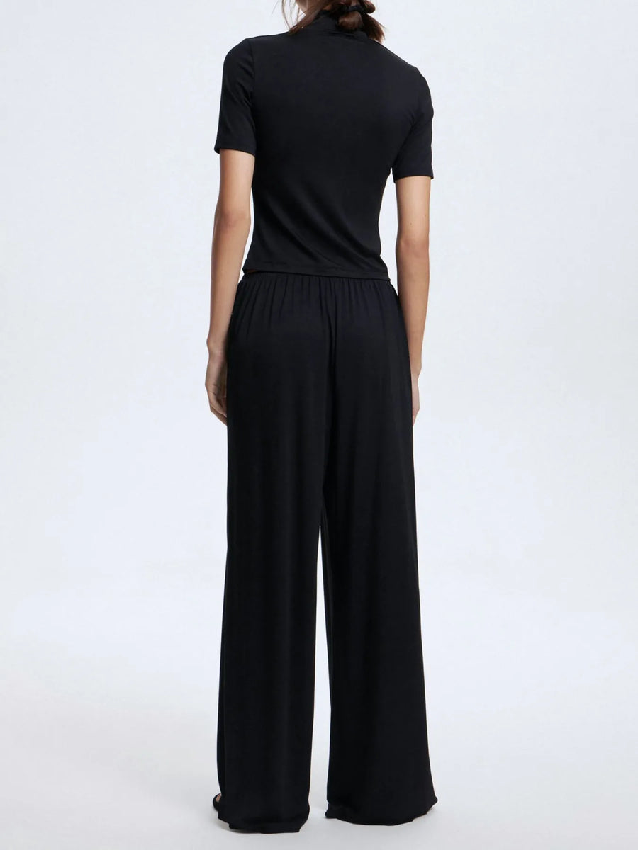 Person wearing a black outfit with wide-leg pants on a white background