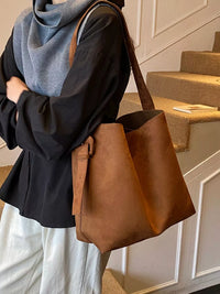 Person holding a brown leather bag in an indoor setting