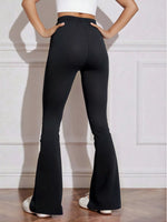 Person wearing black flared pants against a white wall