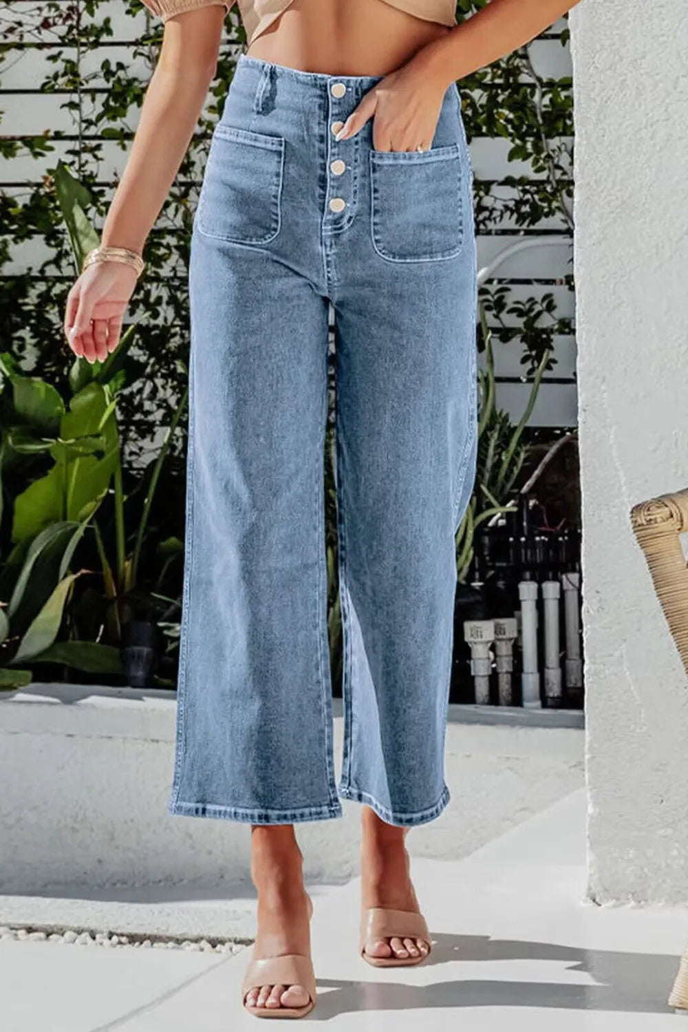 Person wearing light blue wide-leg jeans with a blurred background