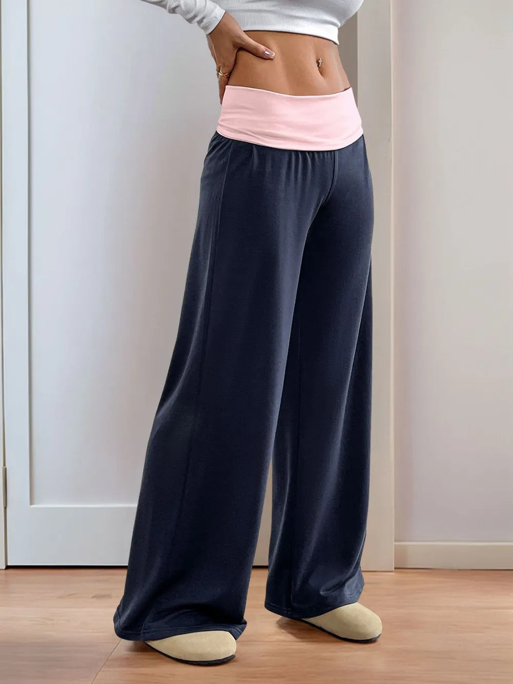 Person wearing navy wide-leg pants with a pink waistband against a white wall.