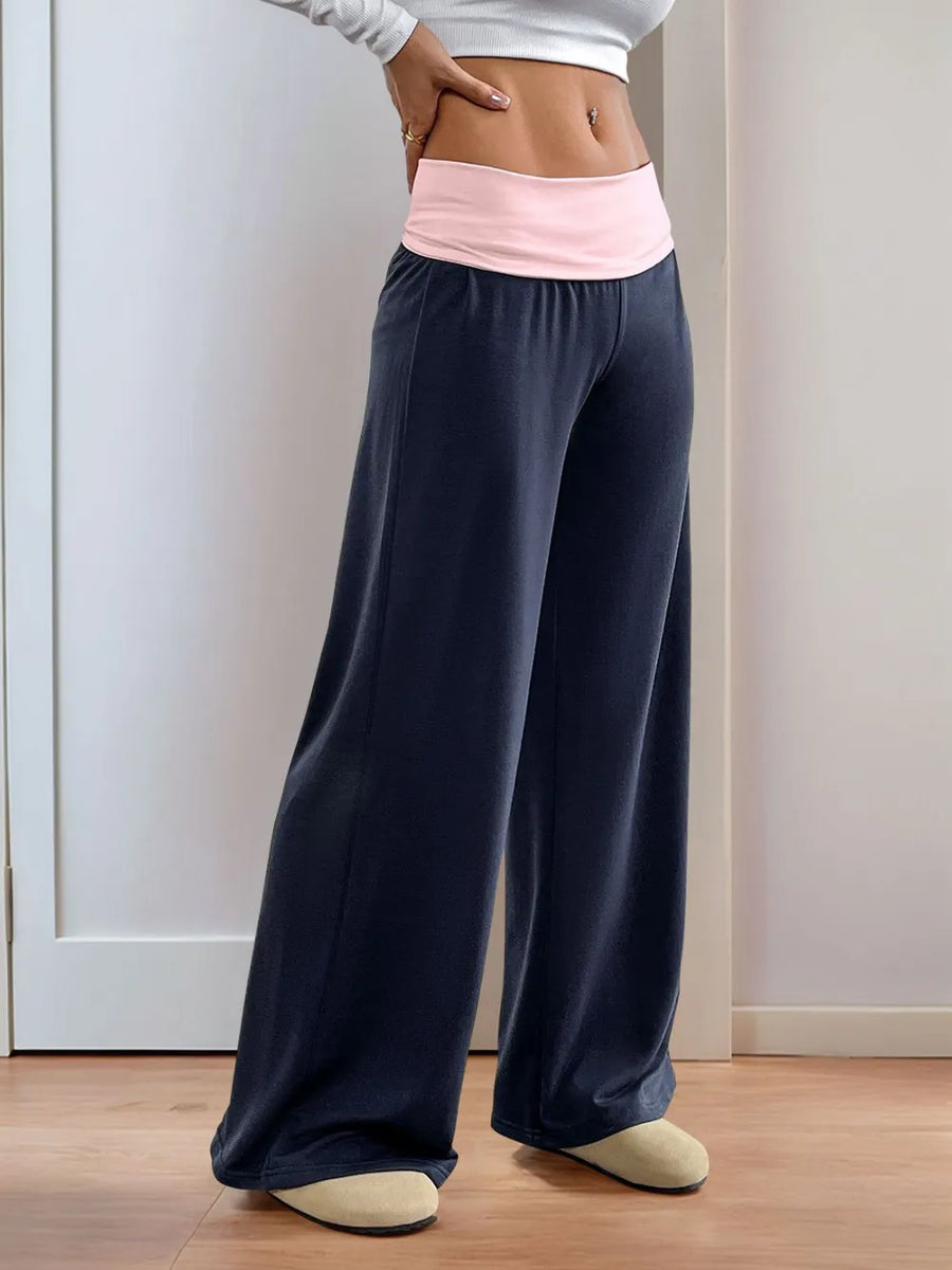 Person wearing navy wide-leg pants with a pink waistband against a white wall.