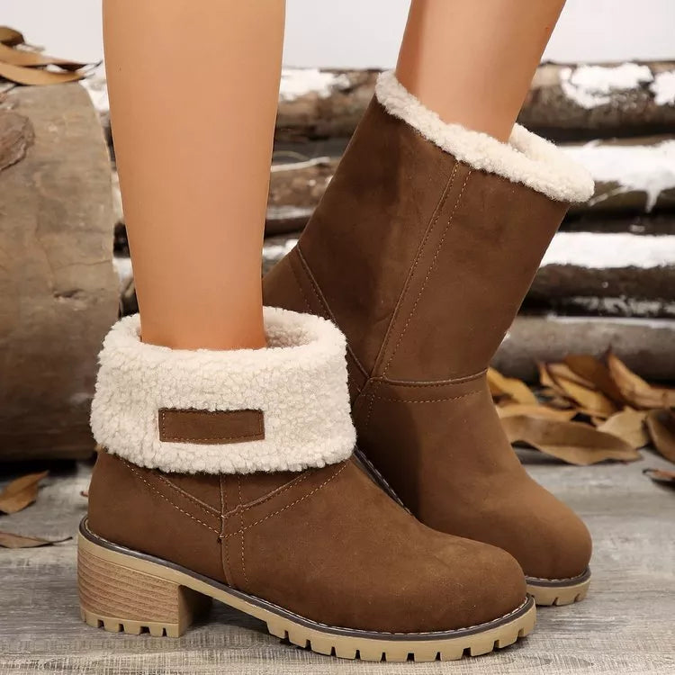 Brown winter boots with white fur trim worn by a person, with a rustic background.