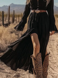 Person wearing a black dress with a belt and leopard print boots in a desert setting