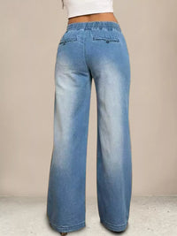 Blue jeans worn by a person on a beige background
