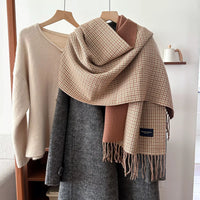 Plaid scarf draped over a coat with a neutral background