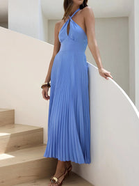 Woman in a blue pleated dress standing on a staircase.