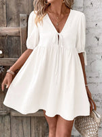 Woman wearing a white dress against a rustic wooden and stone wall.