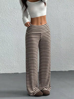 Person wearing a white top and brown and white checkered pants against a plain background
