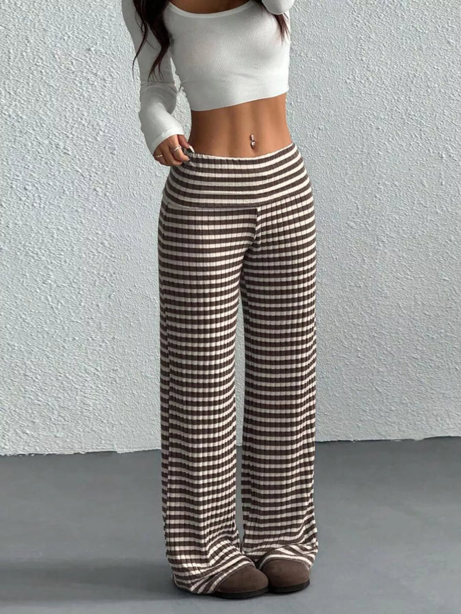Person wearing a white top and brown and white checkered pants against a plain background