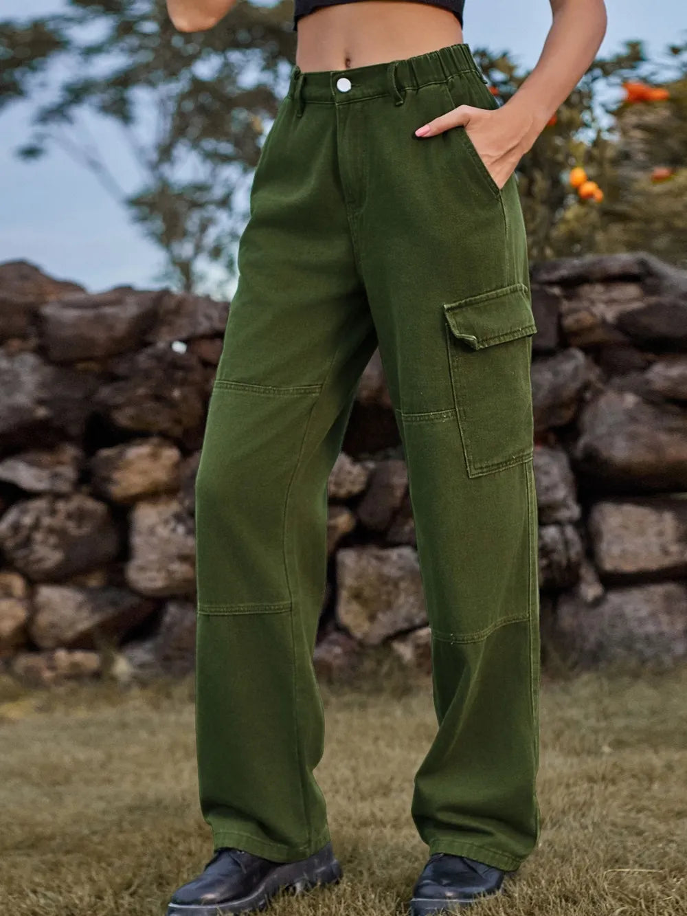 Person wearing green cargo pants standing in front of a stone wall.