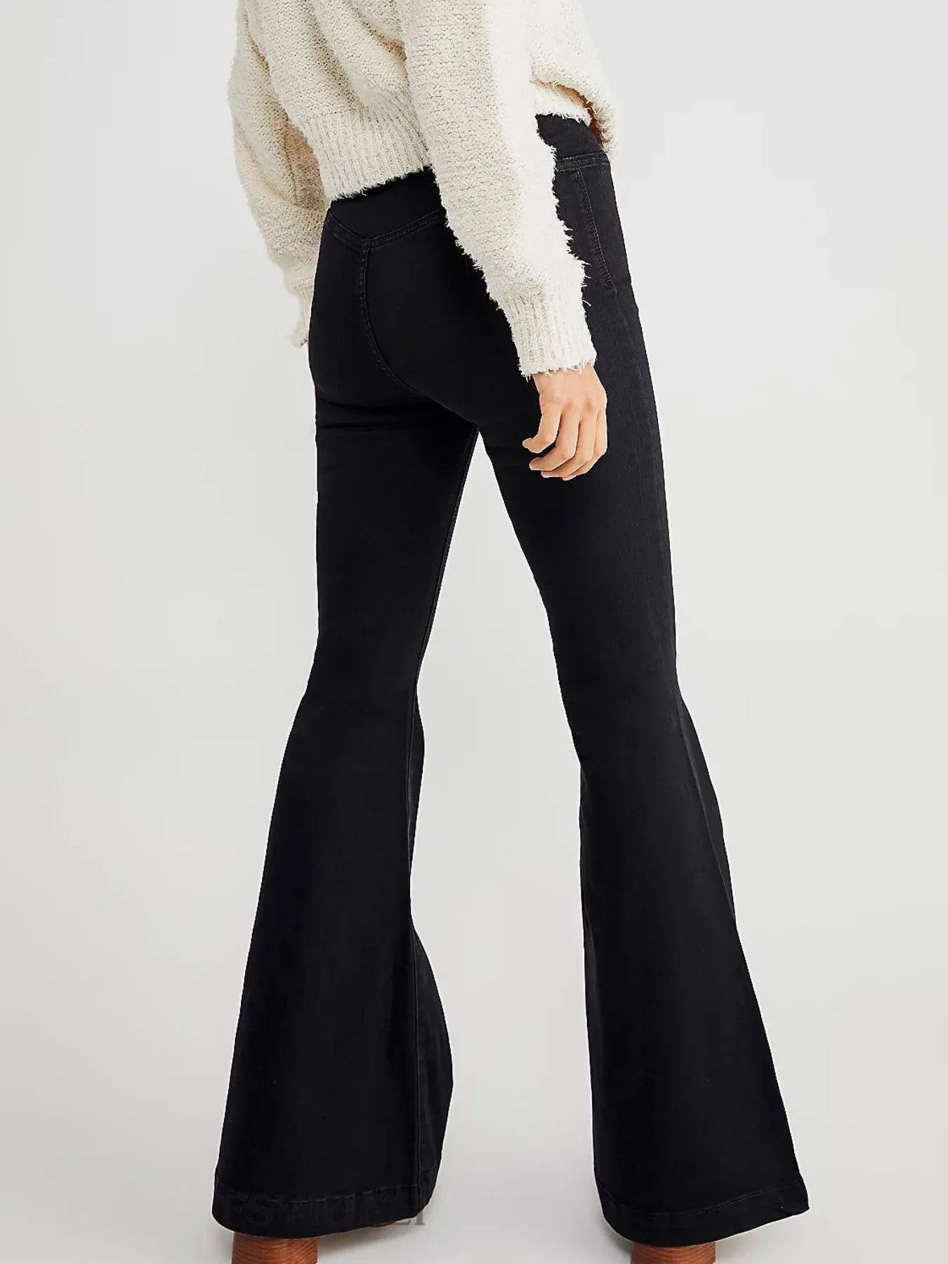 Black flared jeans worn by a person on a white background