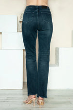 Person wearing dark blue jeans standing in a minimal indoor setting.