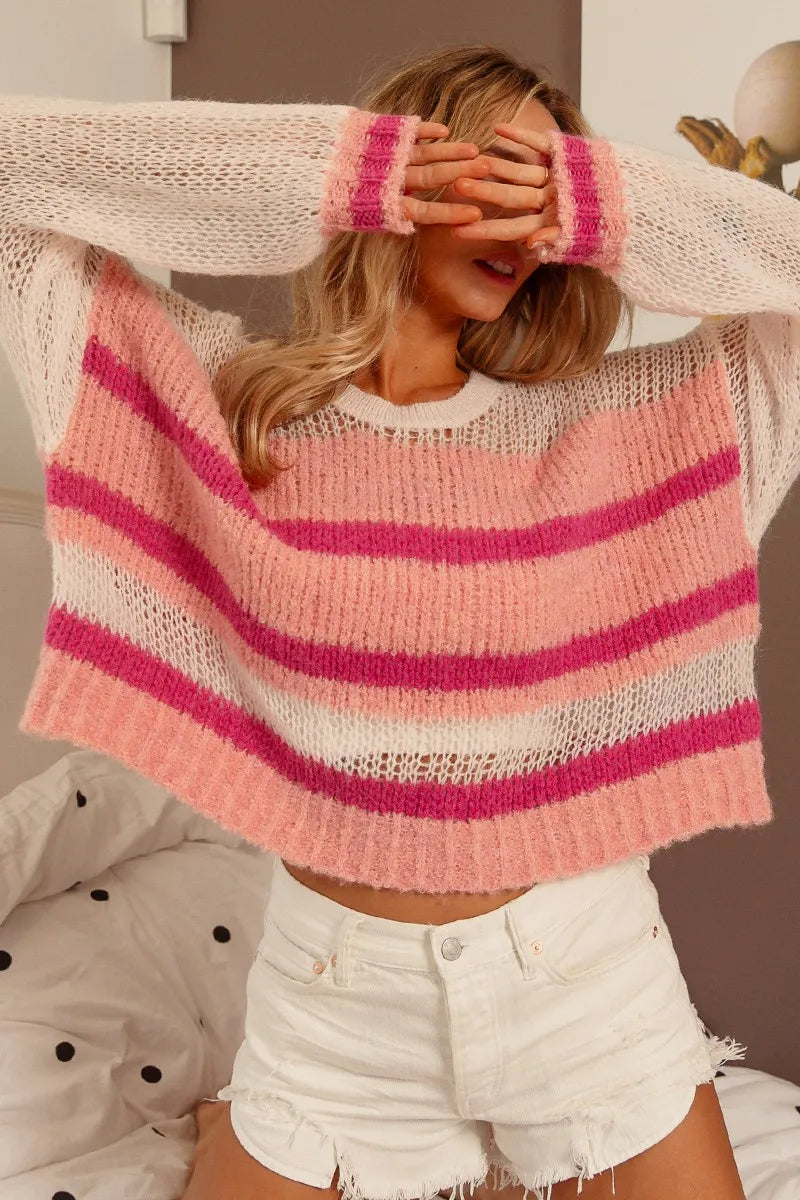 Person wearing a pink and white striped sweater with a blurred background