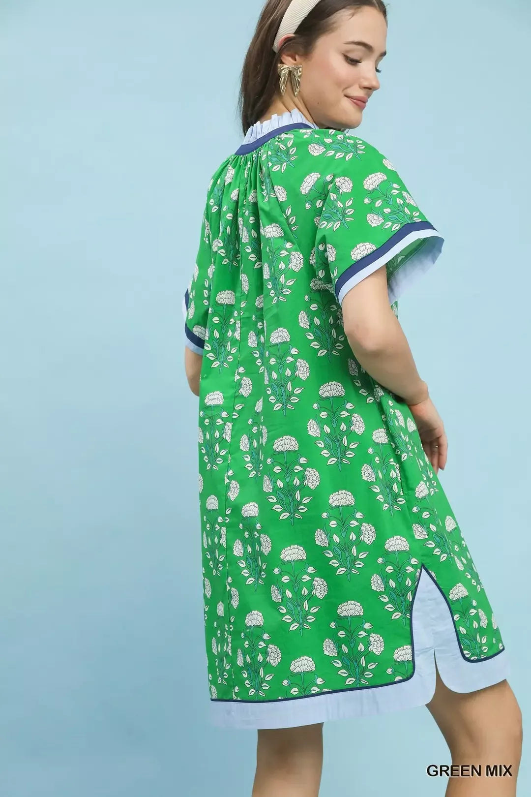 Woman wearing a green dress with white patterns on a light blue background