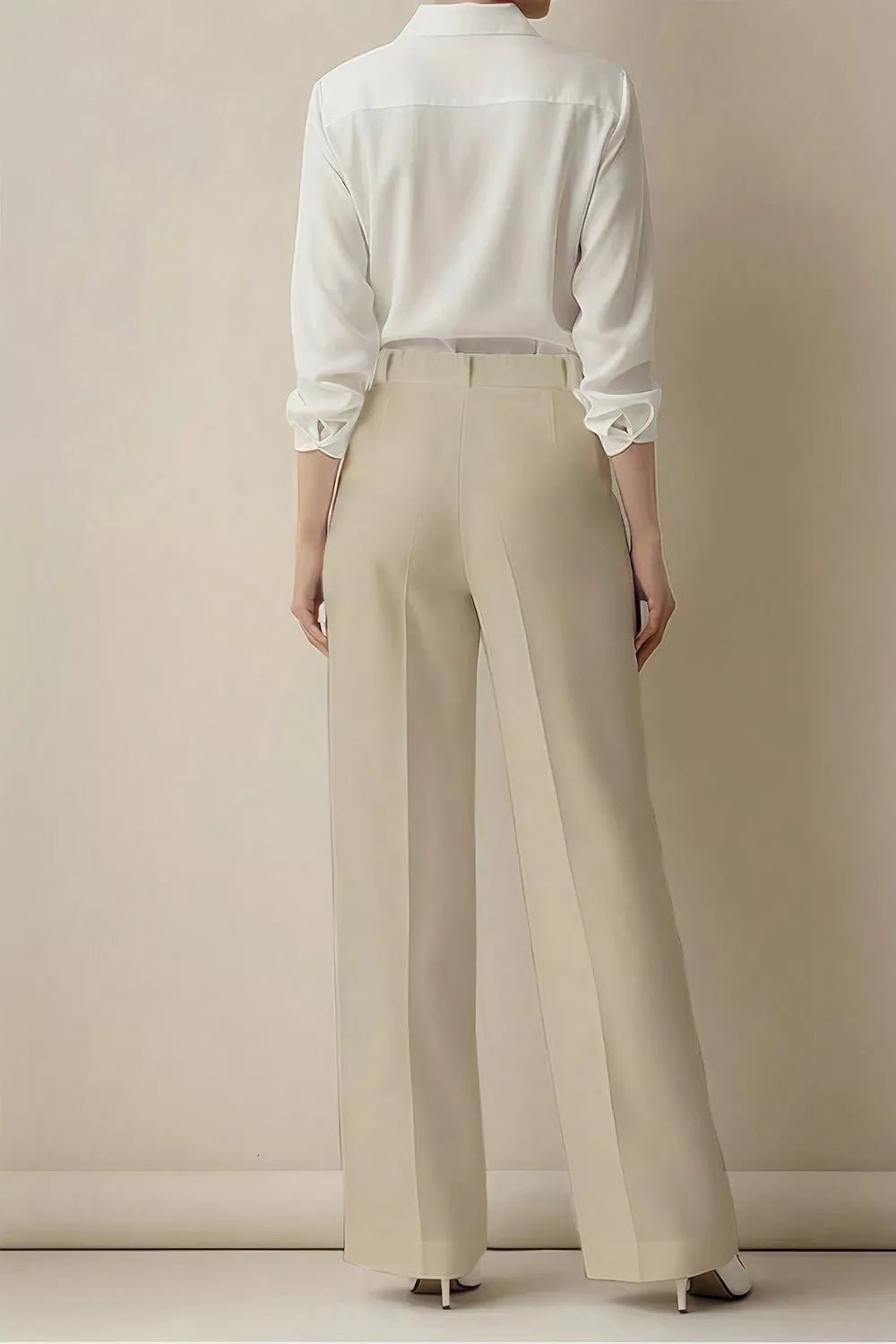 Person wearing a white shirt and beige pants against a plain background