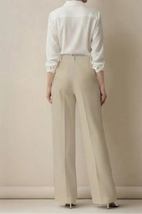 Person wearing a white shirt and beige pants against a plain background
