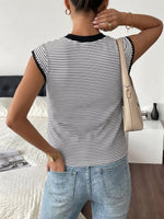 Person wearing a black and white striped sleeveless top and light blue jeans, standing in a room.