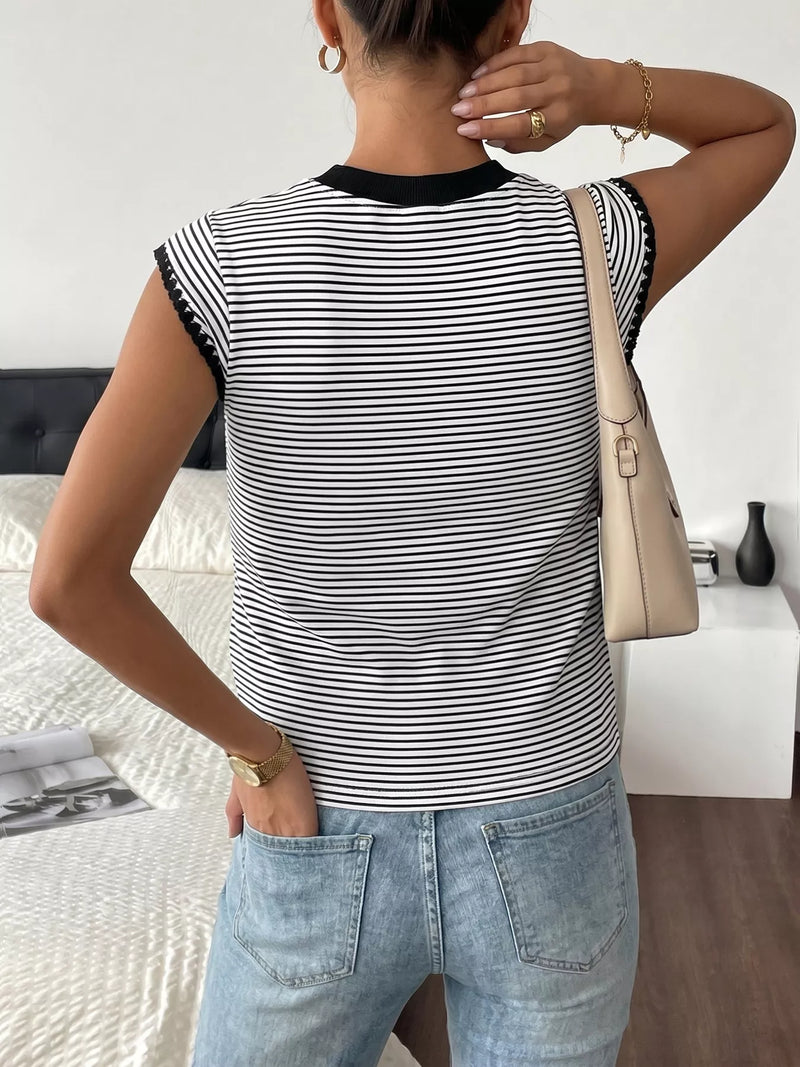Person wearing a black and white striped sleeveless top and light blue jeans, standing in a room.