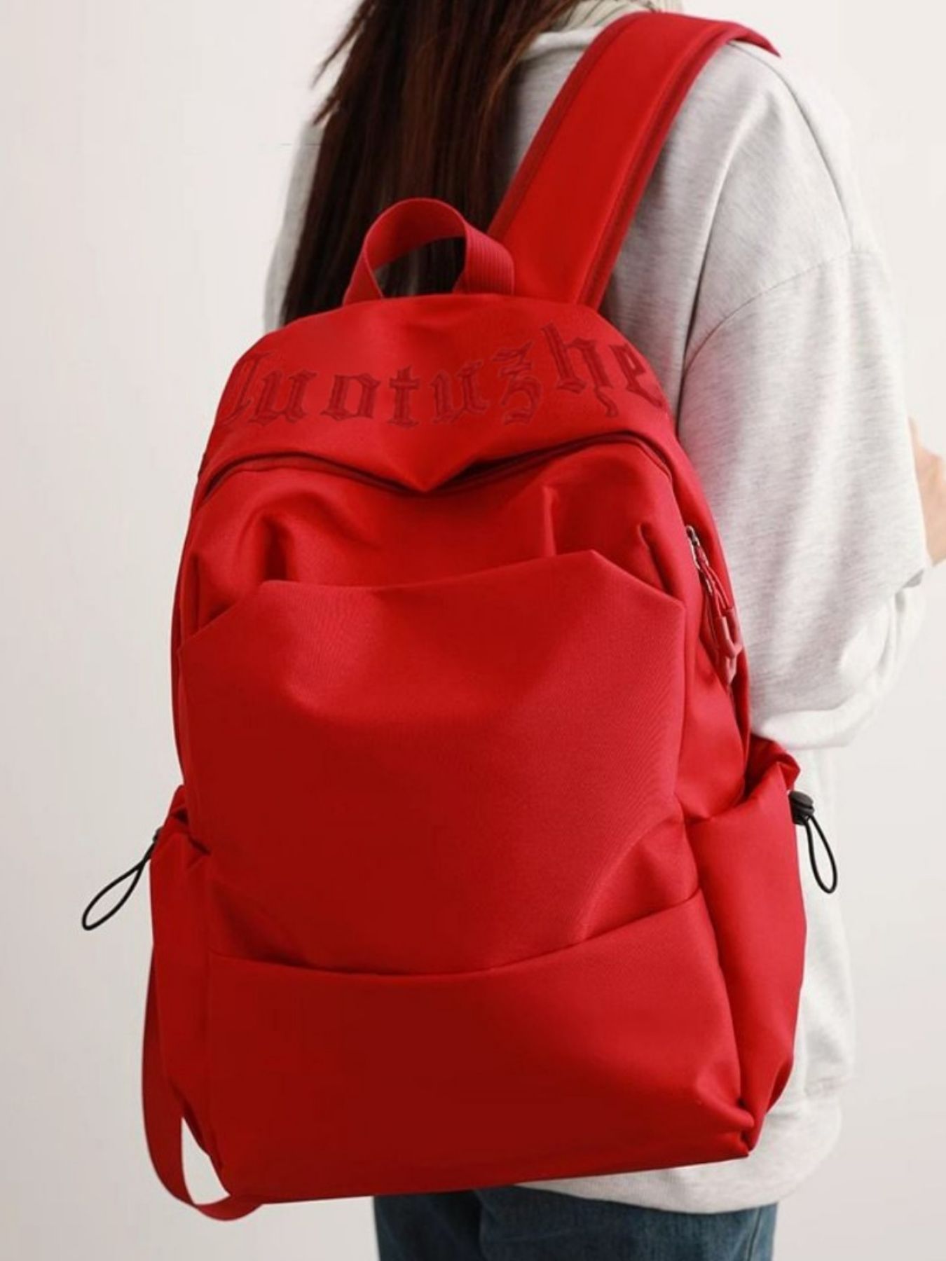 Red backpack worn by a person on a white background