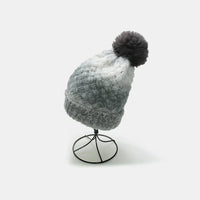 Gray knitted beanie with a pom-pom on a mannequin head against a white background