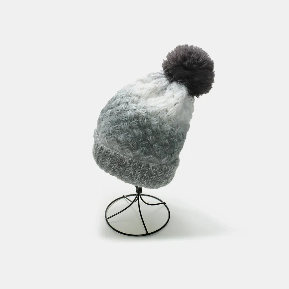 Gray knitted beanie with a pom-pom on a mannequin head against a white background