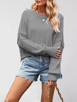 Person wearing a gray sweater and denim shorts on a plain background