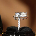 Silver ring with a large diamond on a black stand against a brown background