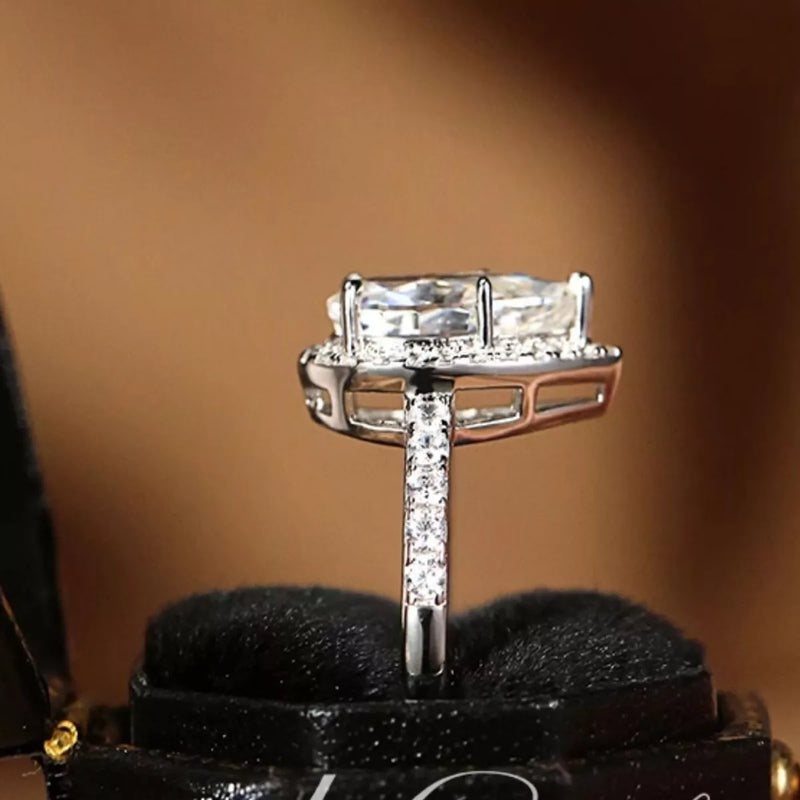 Silver ring with a large diamond on a black stand against a brown background