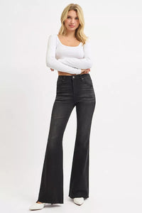 Woman wearing black flared jeans and a white top on a white background