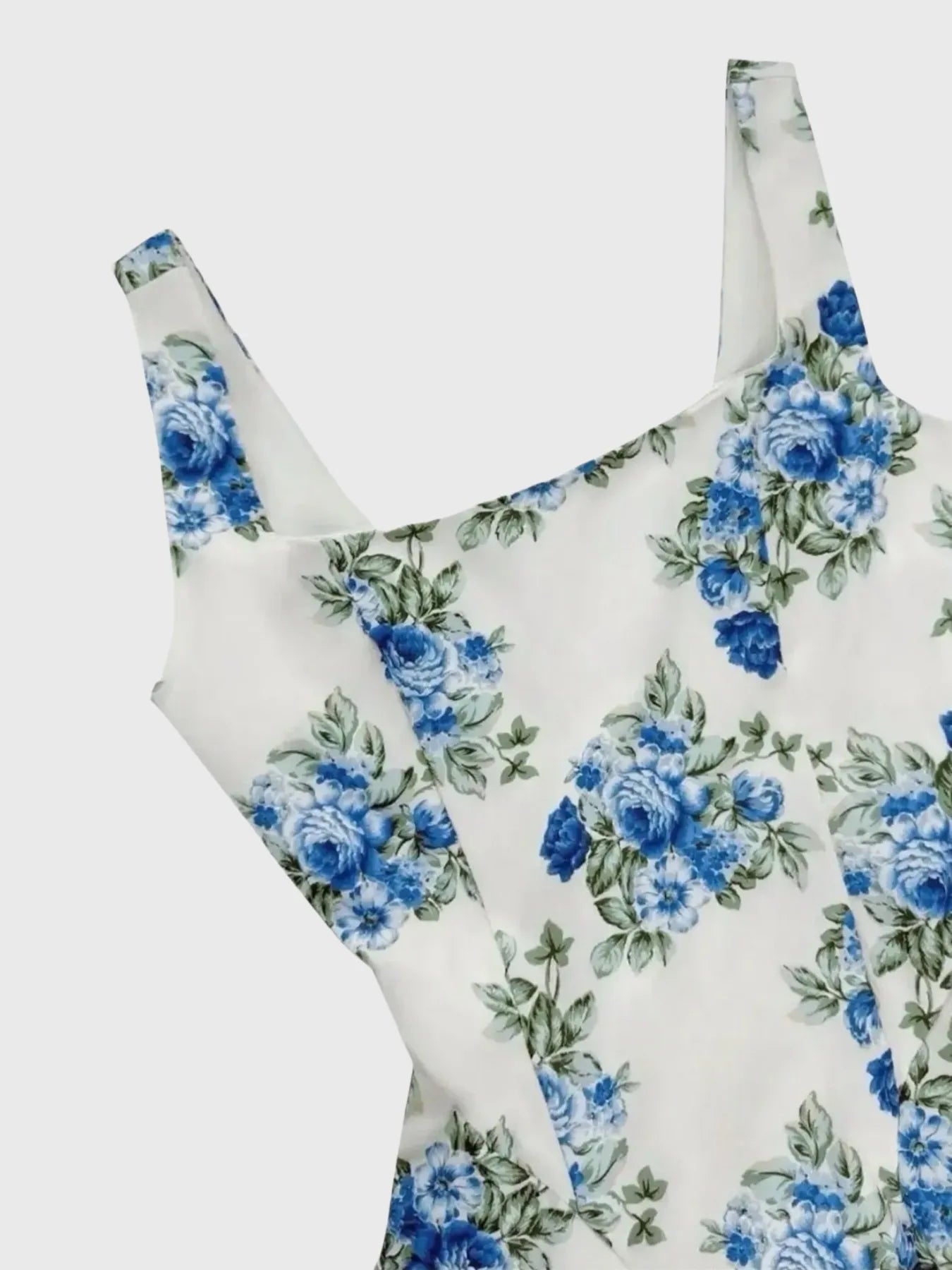 White swimsuit with blue floral pattern on a light gray background