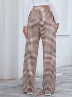 Person wearing brown and white checkered pants with a white top against a light background