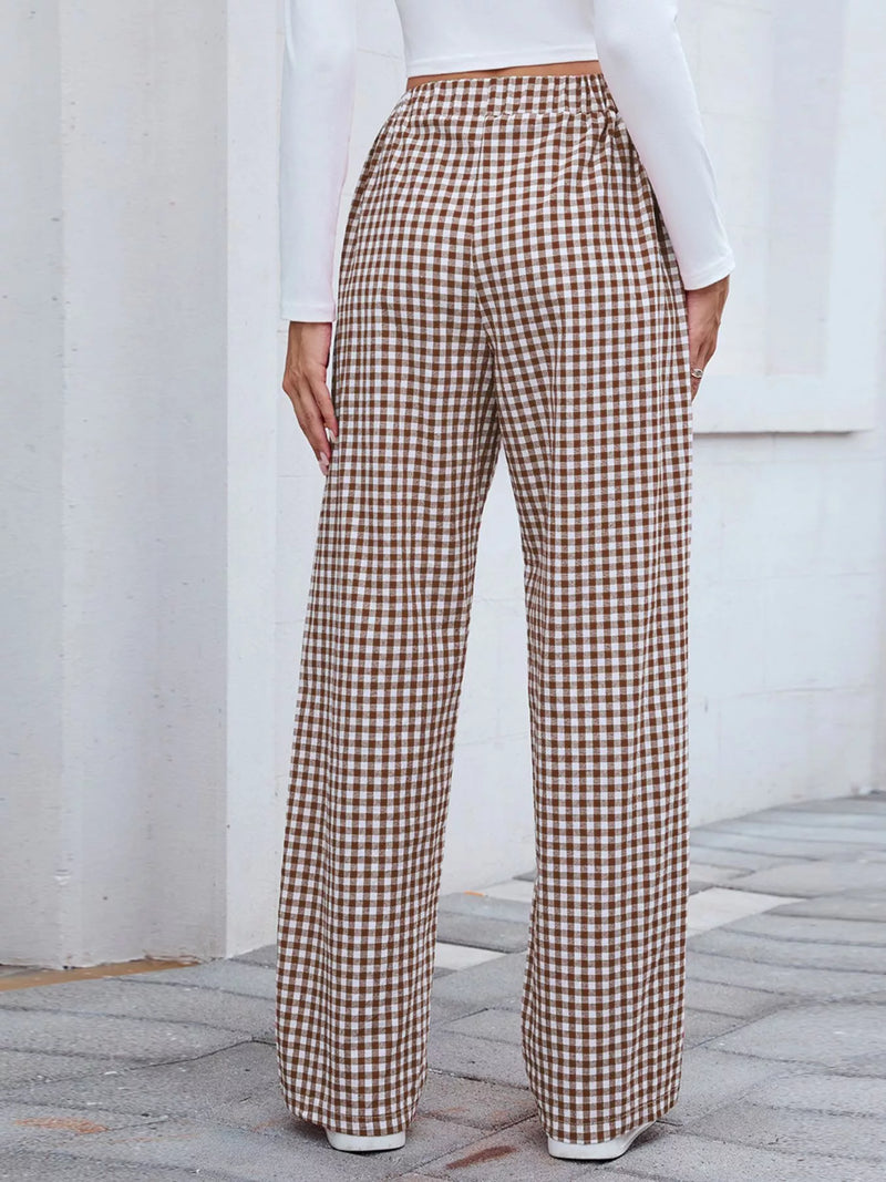 Person wearing brown and white checkered pants with a white top against a light background