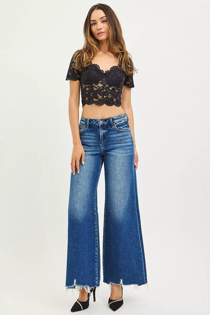 Woman wearing a black lace top and blue jeans on a white background