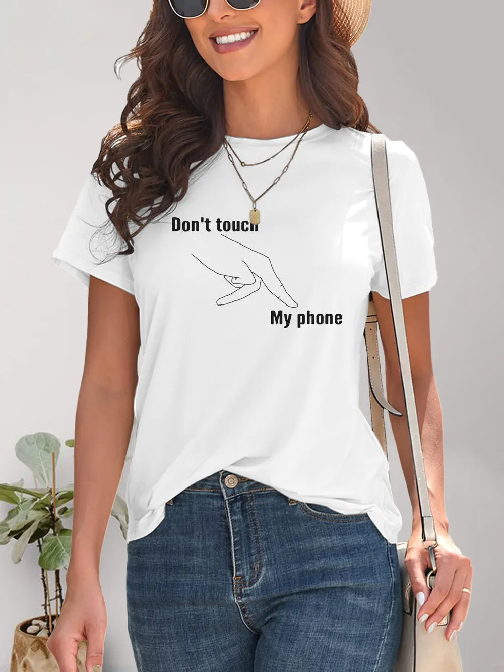 Woman wearing a white t-shirt with text and graphics, standing against a neutral background.