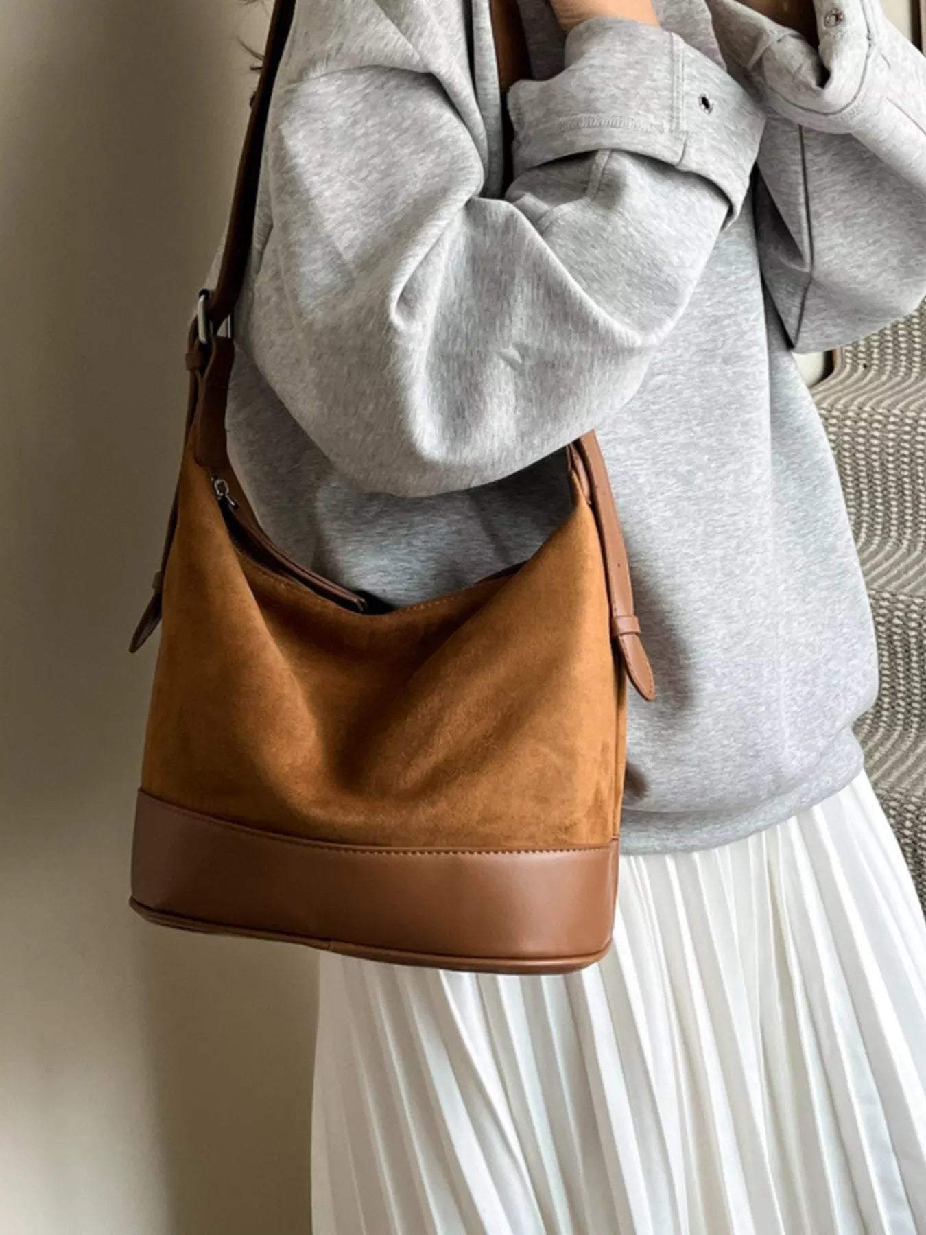 Person wearing a brown leather bag with a neutral background