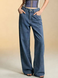 Person wearing blue wide-leg jeans on a beige background