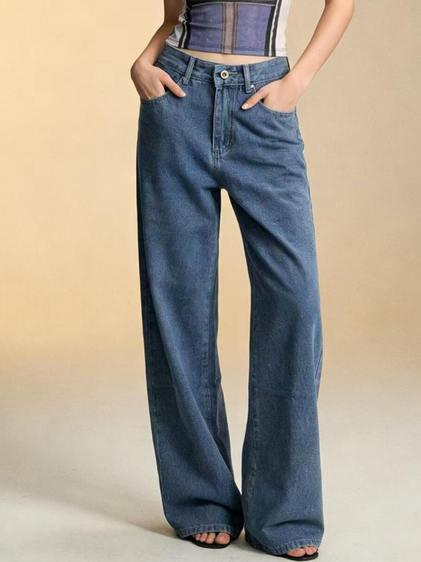 Person wearing blue wide-leg jeans on a beige background