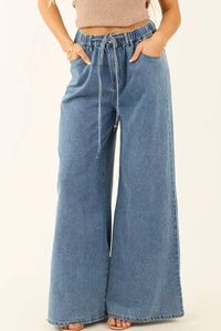 Wide-leg jeans worn by a person on a beige background