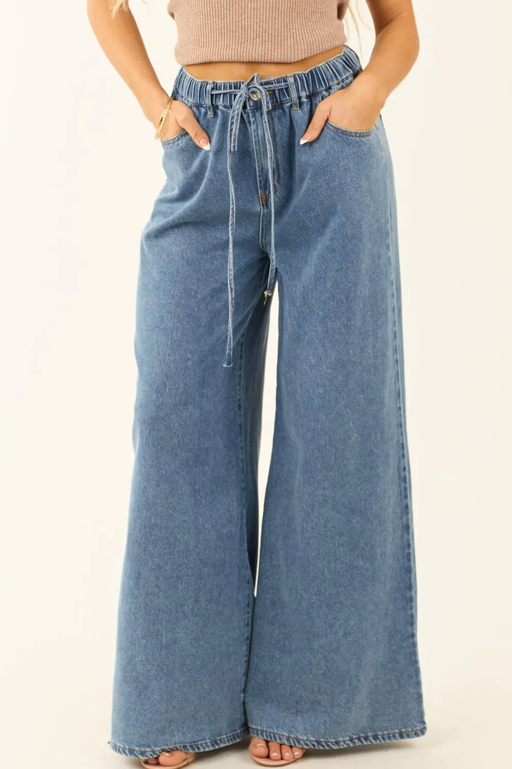Wide-leg jeans worn by a person on a beige background