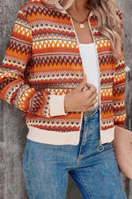 Person wearing a patterned cardigan with orange, red, and white colors, paired with blue jeans.