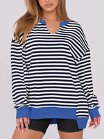 Person wearing a black and white striped sweater with blue accents on a plain background
