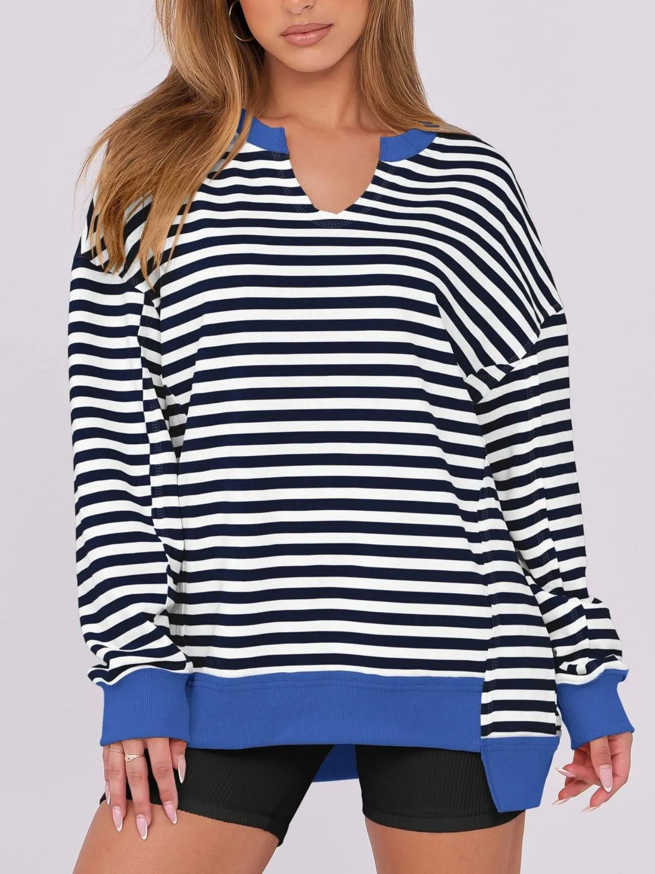 Person wearing a black and white striped sweater with blue accents on a plain background